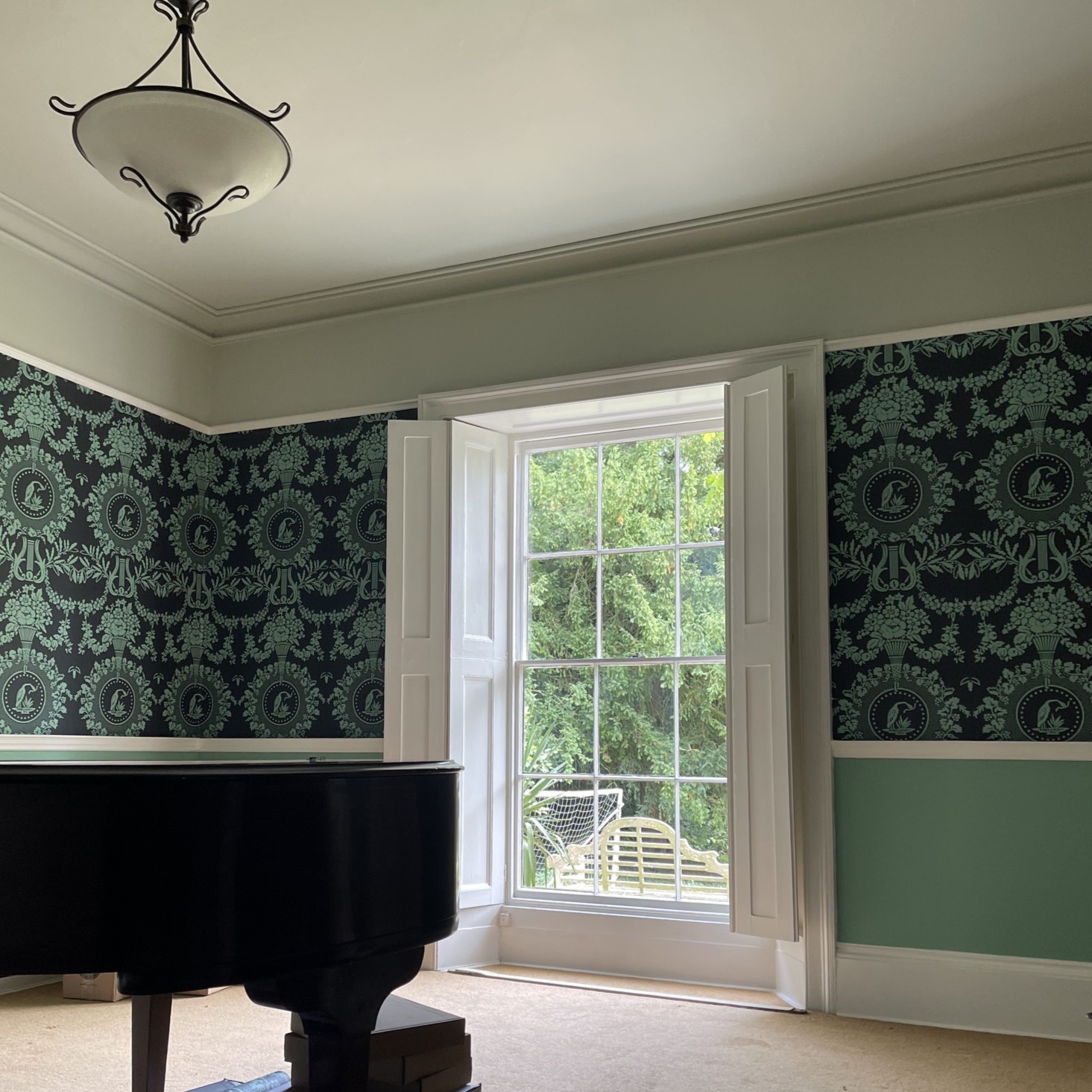 A finished bedroom with teal walls and coordinated floral wallpaper