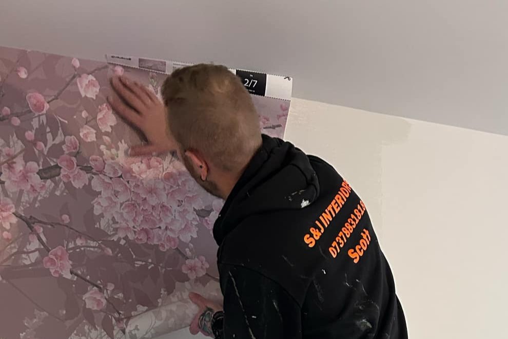 S&J Interiors decorator hanging a feature wallpaper